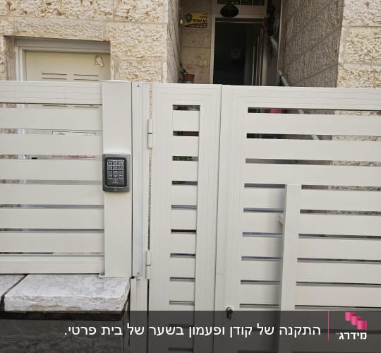 שער עם מקלדת כניסה ליד מבנה אבן